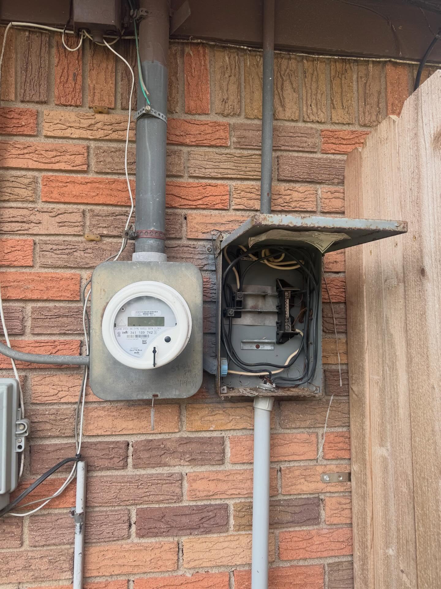Aging residential electric meter and service disconnect being diagnosed on a brick home