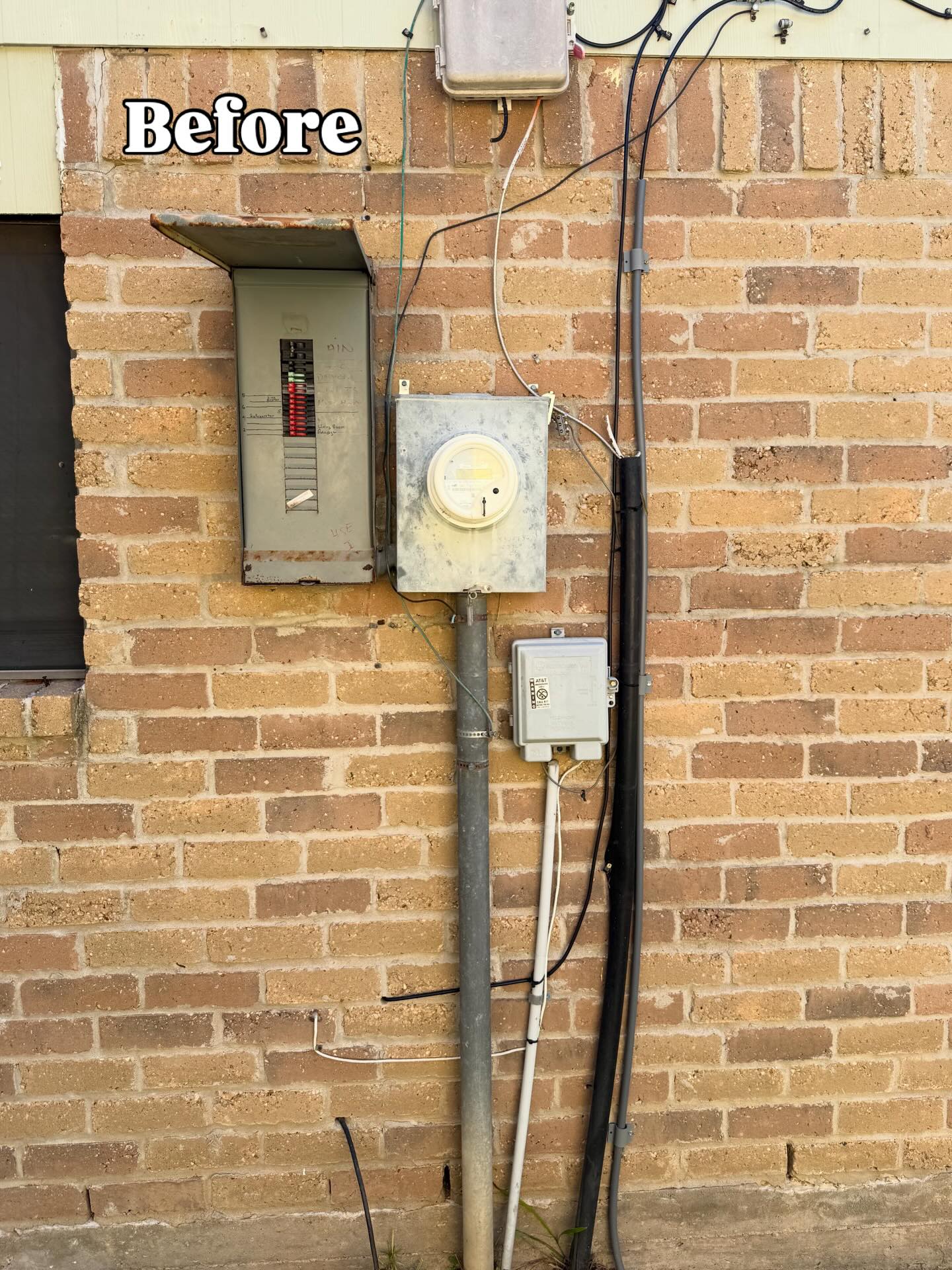 Outdated fuse panel and electric meter on the brick exterior of a home before replacement