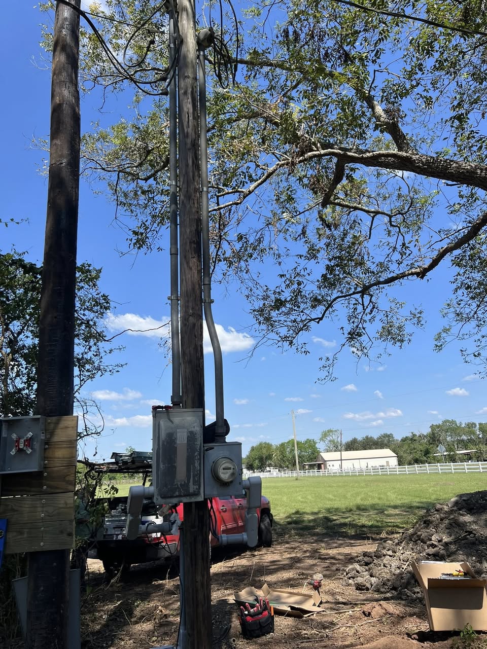 Overhead electrical service work on a rural property with the red Texan Electric work truck on site